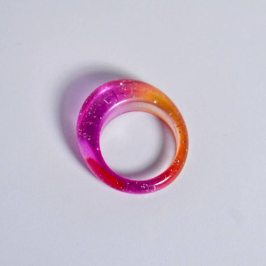 Kare beyaz arkaplanda izole edilmiş pembe ve turuncu şeffaf reçine halka nesnesi.