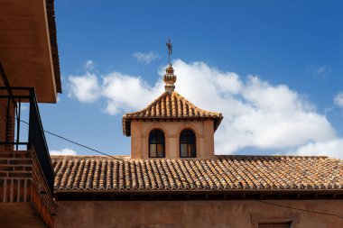 An old Spanish village among the golden fields of Castilla La Mancha on a sunny day with rich blue skies and white fluffy clouds