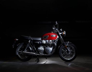 February 2022 - Albacete - Red classic motorcycle Triumph Bonneville T100 in the dark 