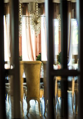 View of the dining room with large windows with curtains and beautiful expensive furniture through a glass door with distortions