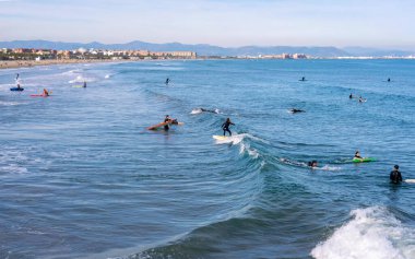 Aralık 2022 - Valencia, İspanya - Yürüyen insanlar ve sörfçülerle dolu Akdeniz