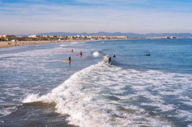 Aralık 2022 - Valencia, İspanya - Yürüyen insanlar ve sörfçülerle dolu Akdeniz