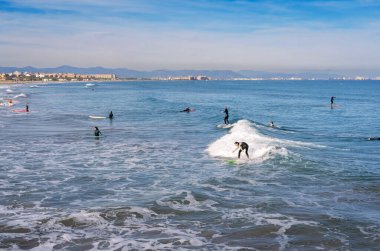 Aralık 2022 - Valencia, İspanya - Yürüyen insanlar ve sörfçülerle dolu Akdeniz