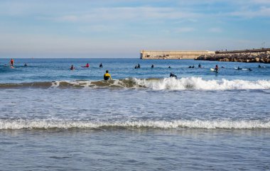 Aralık 2022 - Valencia, İspanya - Yürüyen insanlar ve sörfçülerle dolu Akdeniz