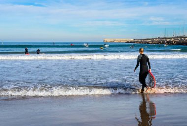 Aralık 2022 - Valencia, İspanya - Yürüyen insanlar ve sörfçülerle dolu Akdeniz