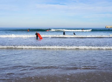 Aralık 2022 - Valencia, İspanya - Yürüyen insanlar ve sörfçülerle dolu Akdeniz