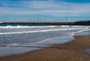 Aralık 2022 - Valencia, İspanya - Yürüyen insanlar ve sörfçülerle dolu Akdeniz