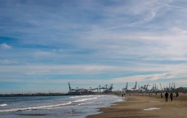 Aralık 2022 - Valencia, İspanya - Yürüyen insanlar ve sörfçülerle dolu Akdeniz