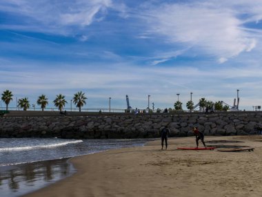 Aralık 2022 - Valencia, İspanya - Yürüyen insanlar ve sörfçülerle dolu Akdeniz