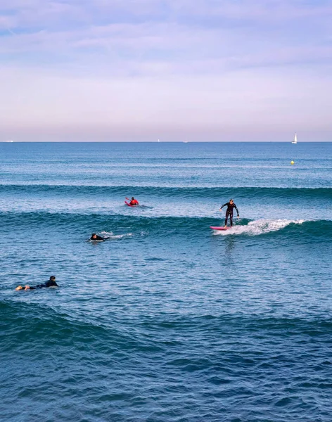 stock image December 2022 - Valencia, Spain - Winter mediterranean sea with crowds of walking people and surfers