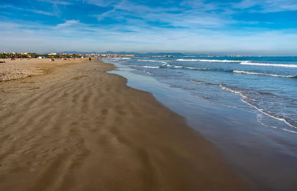 Aralık 2022 - Valencia, İspanya - Yürüyen insanlar ve sörfçülerle dolu Akdeniz
