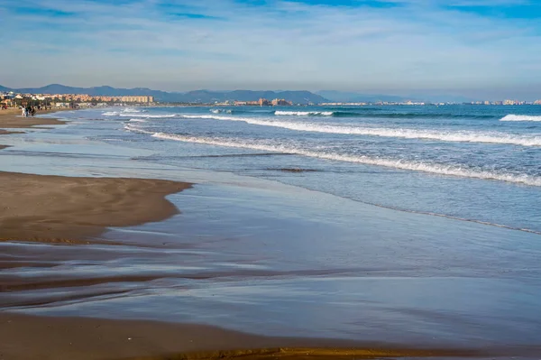 stock image December 2022 - Valencia, Spain - Winter mediterranean sea with crowds of walking people and surfers