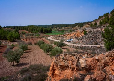 Terracotta renkli toprakları, ton perspektifi ve ağaç plantasyonları olan güzel dağ manzarası.