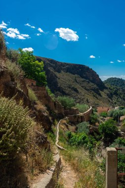 Bir İspanyol köyünde, güneşli bir günde çatıların üstündeki dağ yamacına çıkan dağ yolu.