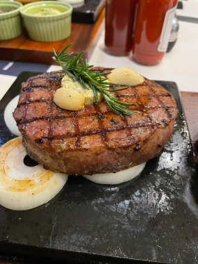 A medium-well steak served in a hotplate with garlic and butter.
