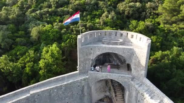 この4Kドローンの映像でStonの歴史的な壁を詳しく見て 風に揺れるクロアチアの旗の誇り高いディスプレイをキャプチャするためにズームインしています — ストック動画