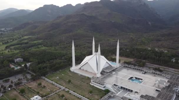 パキスタンのイスラマバードの評判の良い風景の中に囲まれた現代イスラーム建築のシンボルであるファイサル モスクを包む印象的な4Kドローンショット — ストック動画