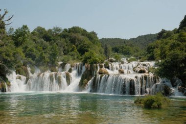 Büyüleyici bir görüntü Krka Şelaleleri, doğanın ham gücünü ve güzelliğini gözler önüne seriyor. Su kayalık bir araziye dökülüyor..