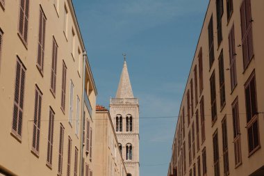 Zadar 'ın tarihi saat kulesi ve kentin tarihi merkezindeki zamansız evlerin eşsiz bir karışımını yakalayan bir atmosferik çekim, Hırvat duvar halısını gösteriyor.