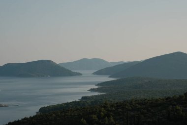 Bu fotoğraf, deniz kenarındaki sisli Hırvat tepelerinin ruhani güzelliğini yansıtıyor. Gün ağarırken, tepelerin siluetleri sisle örtülü olarak ortaya çıkar..