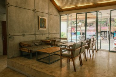 Beton duvarları, sıcak ahşap bir sehpası ve yeşil mobilyaları olan şık bir Alman restoranını deneyin..