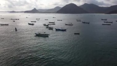 Lombok 'un sahil şeridinin sinematik cazibesini gözler önüne sererken dron zarifçe süzülüyor ve denizde dans eden balıkçı teknelerinin büyüleyici bir duvar halısını yakalıyor..