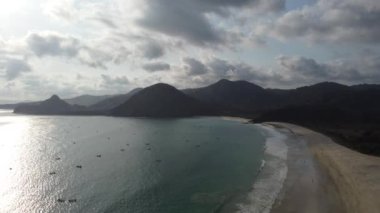 Lombok, Endonezya 'daki Selong Belanak Sahili' nin nefes kesici güzelliğinin üzerinde süzül. İnsansız hava aracı el değmemiş kumlu sahili yakalar. Gök mavisi sular koyu mavi bir rengi yansıtır.