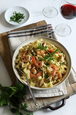 Italian Traditional Dish tagliatelle pasta with shrimp and mushrooms and  garnished with fresh parsley on white background.  Italian pasta. Directly above.