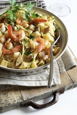 Italian Traditional Dish tagliatelle pasta with shrimp and mushrooms and  garnished with fresh parsley. Italian pasta. Directly above.