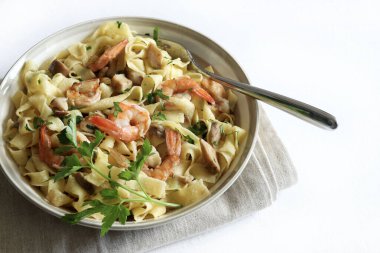 Italian Traditional Dish tagliatelle pasta with shrimp and mushrooms and  garnished with fresh parsley on white background.  Italian pasta. Directly above.