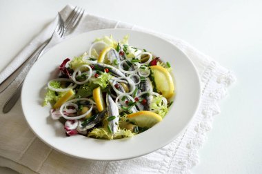 Fresh salad with marinated sardine fillets in white bowl. White sardine fillets. Healthy seafood. Vegetarian food.