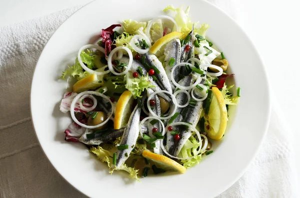 Fresh salad with marinated sardine fillets in white bowl. White sardine fillets. Healthy seafood. Vegetarian food.