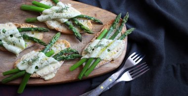 Ahşap kesim tahtasında kuşkonmaz ve peynir bruschetta. Tam üstte. Sağlıklı yemek..