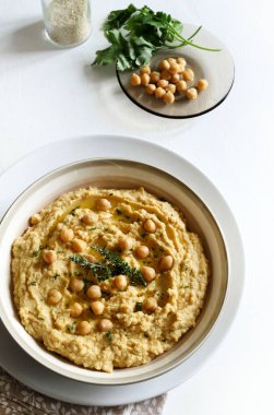 Bowl with hummus, chickpeas, herbs on a white background. Directly above. Vegetarian or vegan food.