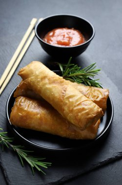 Fried spring rolls with sweet chili sauce on a dark background. Asian cuisine.