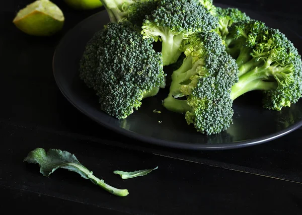 Fresh broccoli and lemon isolated on black background. Close-up.