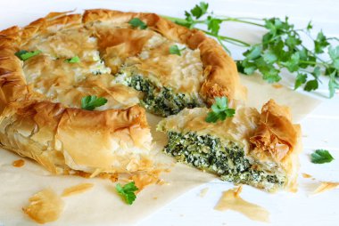 Traditional Greek cuisine. Spanakopita, savory pie. Homemade Greek phyllo dough pie filled with spinach and feta cheese. Close-up.