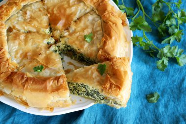 Traditional Greek cuisine. Spanakopita, savory pie. Homemade Greek phyllo dough pie filled with spinach and feta cheese. Close-up.