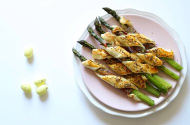 Easter holiday. Top view of roasted asparagus rolls with prosciutto and puff pastry on a table. Easter decoration. Menu concept. Directly above.