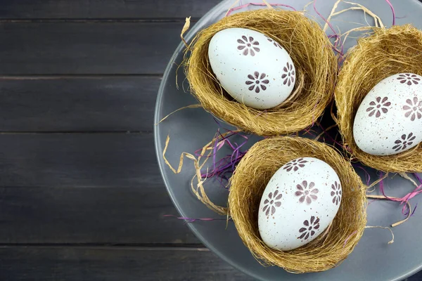 Concept of Easter holiday. Easter eggs in baskets isolated on wooden background. Copy space. Directly above.