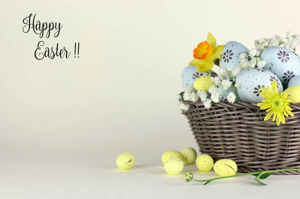 Easter holiday. Easter eggs and flowers in basket with tag on white background.