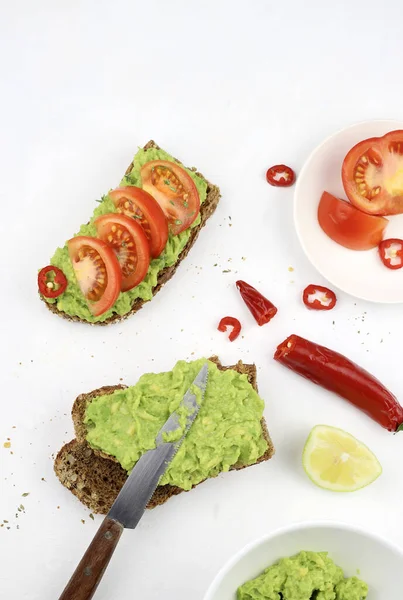 Delicious avocado toast with tomatoes and whole grain bread on white background. Healthy food concept. Vegetarian or vegan food. Directly above.