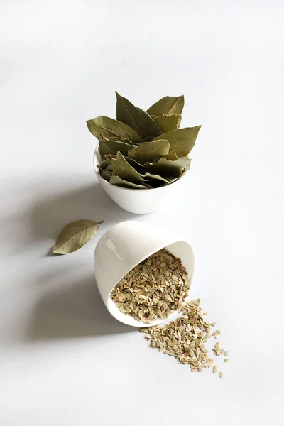 Bay leaf and ground bay leaves in white ceramic bowl. Aromatic plant. Copy space. Directly above.