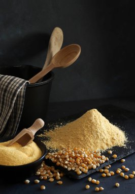 Cornmeal and corn kernels on a black background.