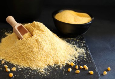Cornmeal and corn kernels on a black background.