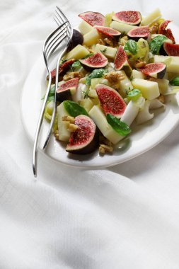 Fresh fig salad with endive, nuts and cheese on a gray background. View from above. Healthy food. Vegetarian food.
