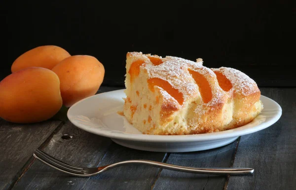 stock image Slice of homemade apricot pie with fresh fruits on a wooden table. Close-up.