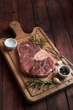 Ahşap kesme tahtasının üzerinde otlu taze ossobuco konservesi. Ağır ateşte pişmiş et. Tam üstte.