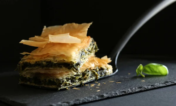 stock image Homemade Greek food. Spanakopita, phyllo pastry triangle with spinach and feta cheese on black background. Copy space. Close-up.