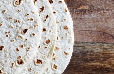 İtalyan piadinasına yakın plan ahşap arka planda izole edilmiş. Düz ekmek, tortilla ekmeği, romagnola piadina. Uzayı kopyala Tam üstte.